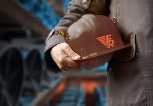 Worker holding a safety helmet with Faragon Restoration Logo on it